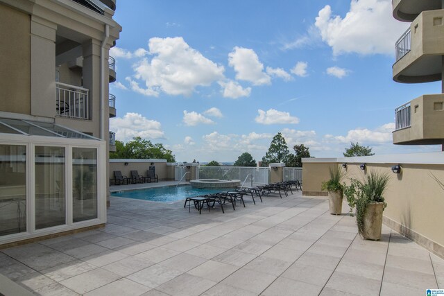 view of patio / terrace featuring a balcony, a fenced in pool, and pool water feature