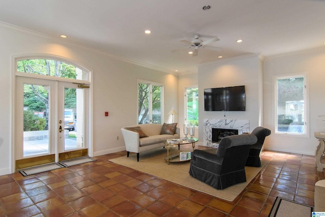 tiled living room featuring ceiling fan, a wealth of natural light, a high end fireplace, and ornamental molding