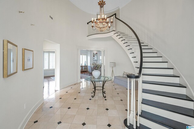 entrance foyer with light tile patterned flooring, a notable chandelier, and a towering ceiling