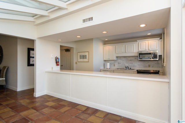 kitchen featuring tasteful backsplash, kitchen peninsula, sink, appliances with stainless steel finishes, and beam ceiling