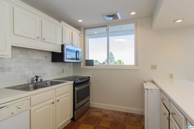 kitchen with appliances with stainless steel finishes, backsplash, white cabinetry, and sink