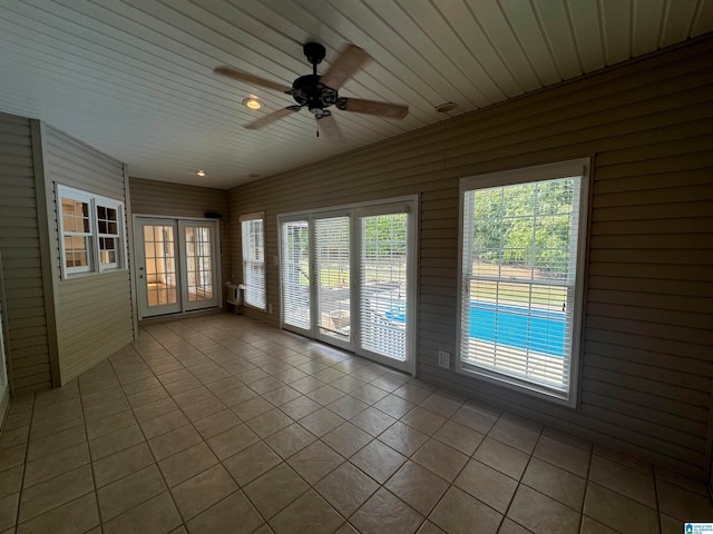 spare room with ceiling fan, wood ceiling, wood walls, and light tile patterned floors