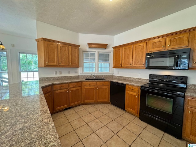 kitchen with light tile patterned floors, sink, a textured ceiling, black appliances, and dark stone counters