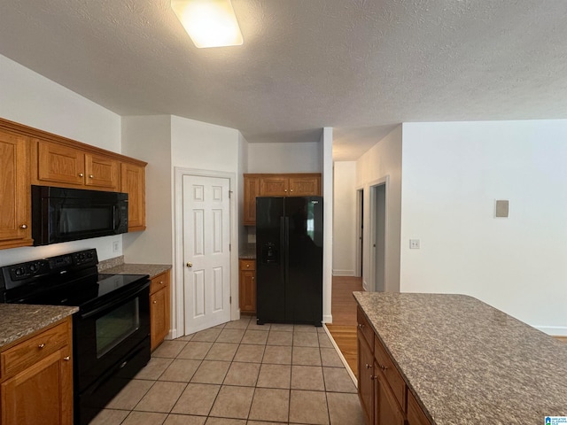 kitchen featuring a textured ceiling, light tile patterned floors, and black appliances