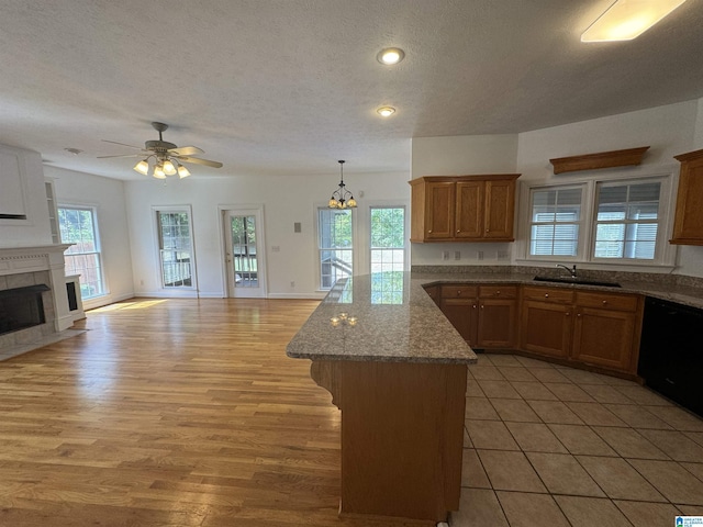 kitchen with brown cabinetry, a peninsula, open floor plan, and a sink