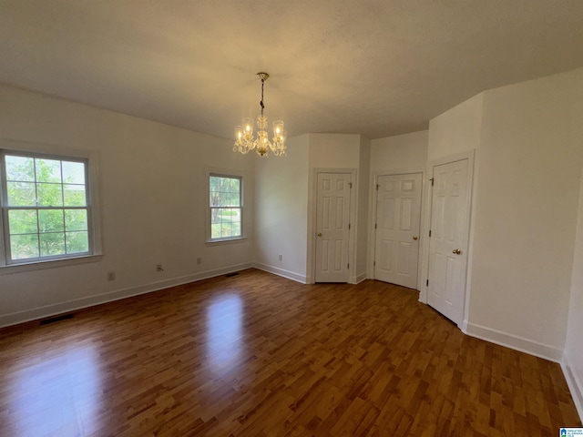 spare room featuring baseboards, visible vents, dark wood-style floors, and a notable chandelier