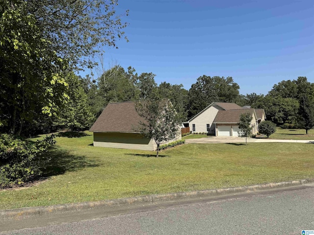 view of property exterior featuring an attached garage, a lawn, and concrete driveway