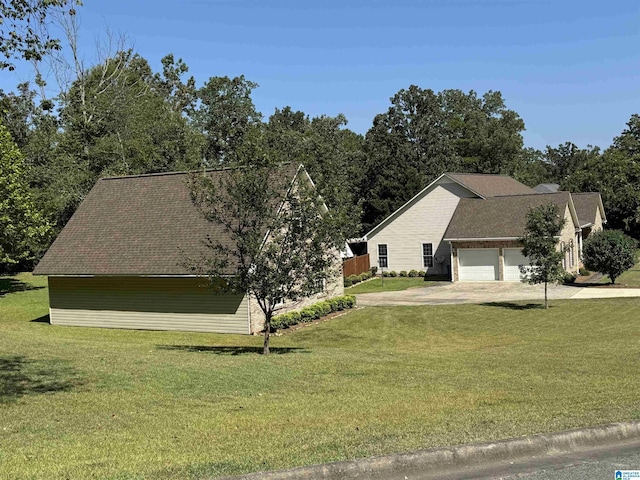 view of side of property featuring an attached garage, a yard, and concrete driveway