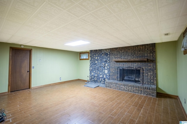 unfurnished living room with hardwood / wood-style flooring and a brick fireplace