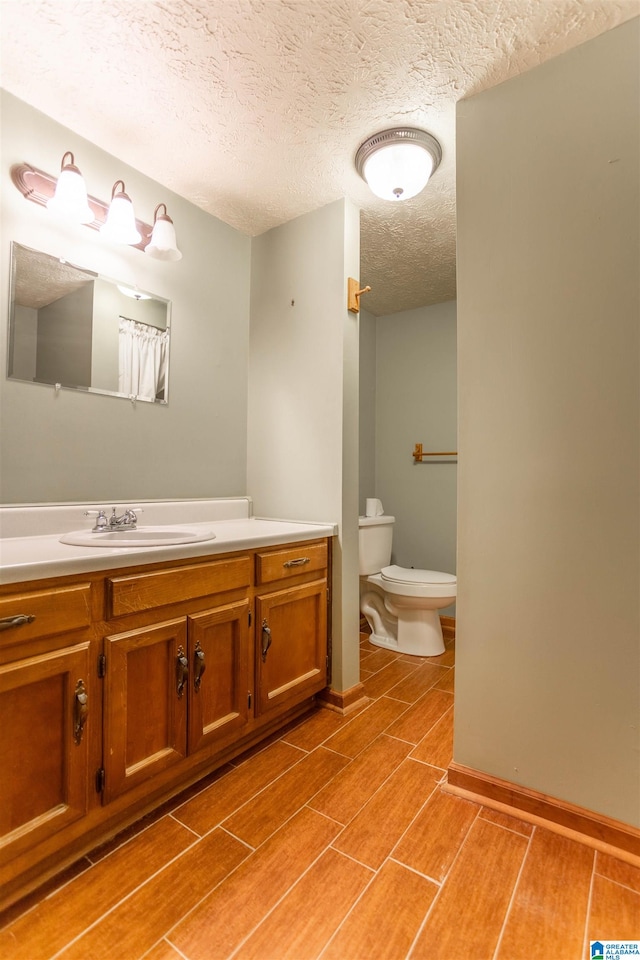 bathroom with toilet, a textured ceiling, and vanity