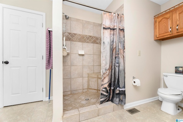 bathroom featuring toilet, a shower with curtain, and tile patterned floors