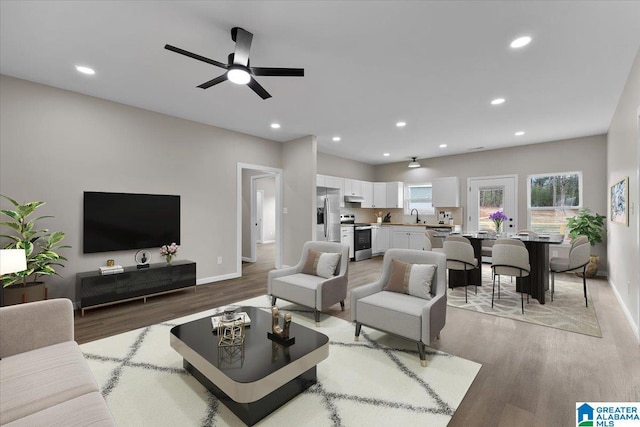 living room with ceiling fan, light hardwood / wood-style flooring, and sink