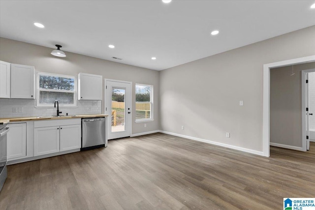 kitchen with wooden counters, white cabinetry, stainless steel dishwasher, and sink