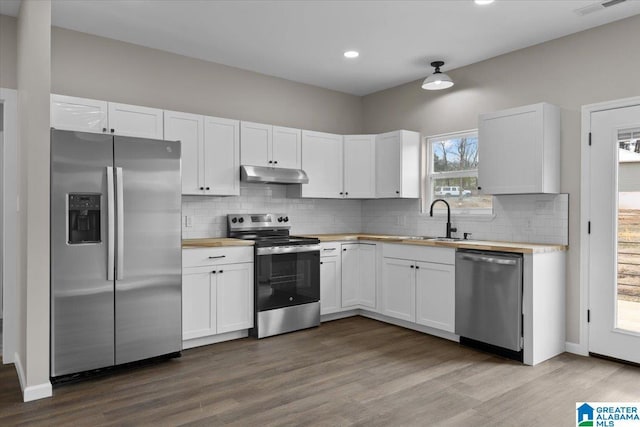 kitchen featuring sink, stainless steel appliances, white cabinetry, and butcher block countertops