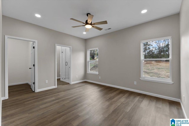 unfurnished bedroom featuring a spacious closet, ceiling fan, and dark wood-type flooring