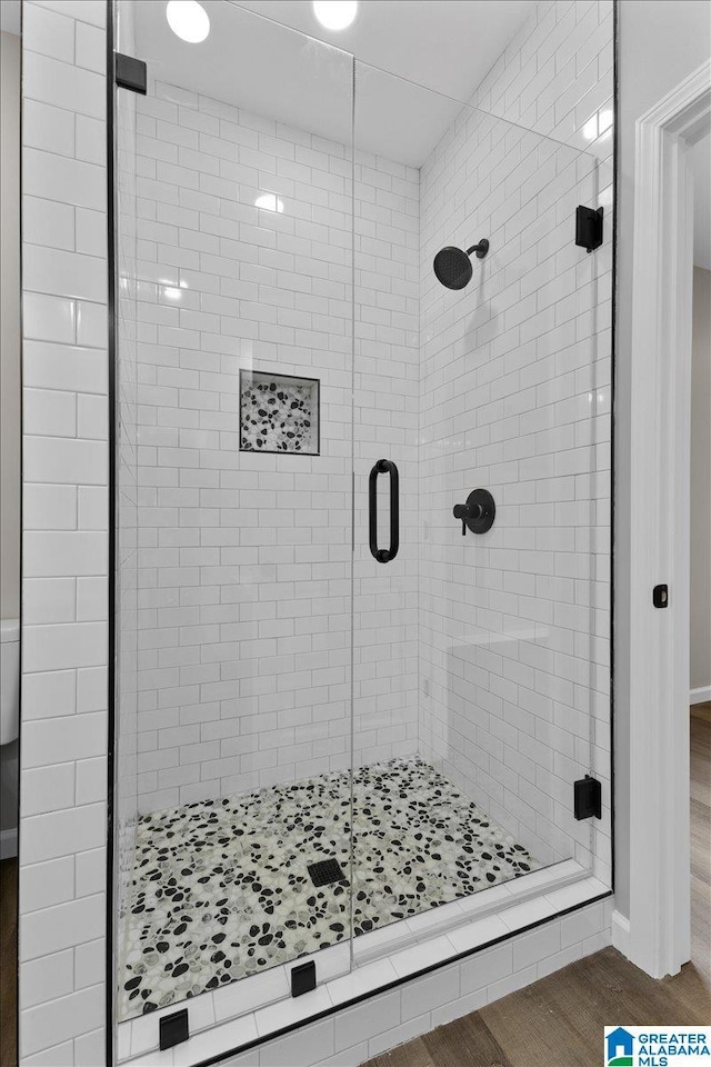 bathroom with wood-type flooring and an enclosed shower