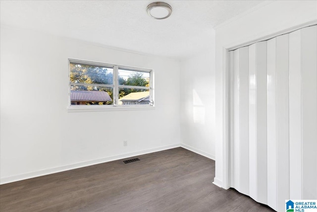 spare room with dark hardwood / wood-style floors and a textured ceiling