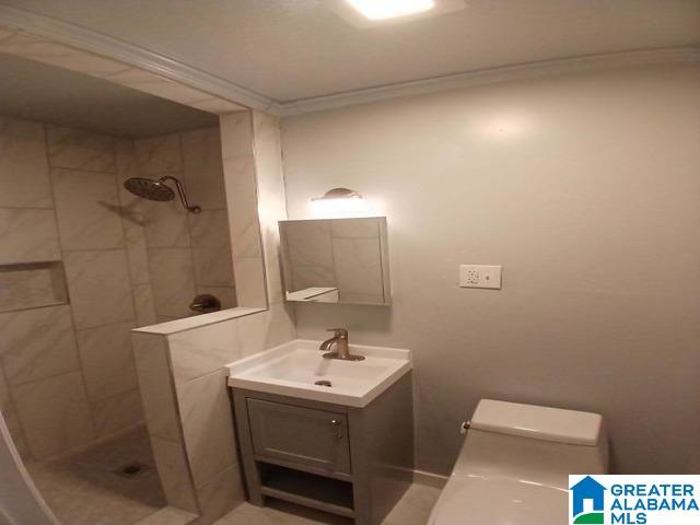 bathroom with toilet, vanity, and tiled shower