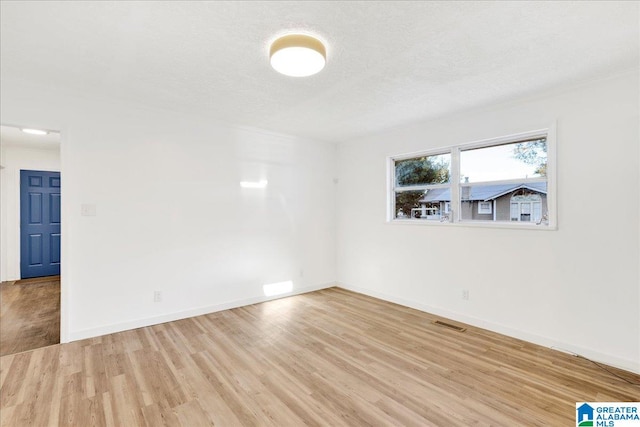 spare room featuring light hardwood / wood-style flooring and a textured ceiling