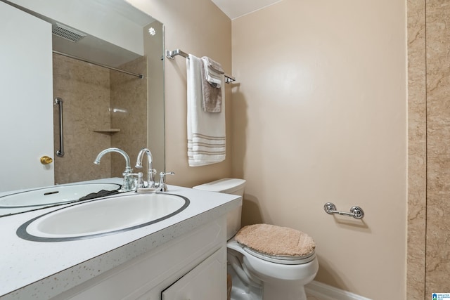 bathroom featuring vanity, toilet, and tiled shower