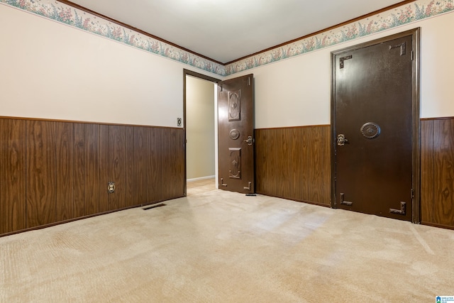 carpeted empty room featuring wooden walls