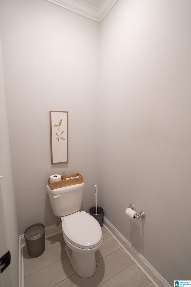 bathroom featuring tile patterned floors, crown molding, and toilet