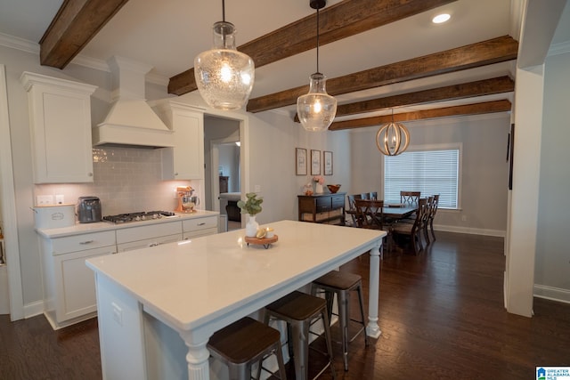 kitchen with custom exhaust hood, white cabinets, dark hardwood / wood-style floors, decorative light fixtures, and stainless steel gas cooktop