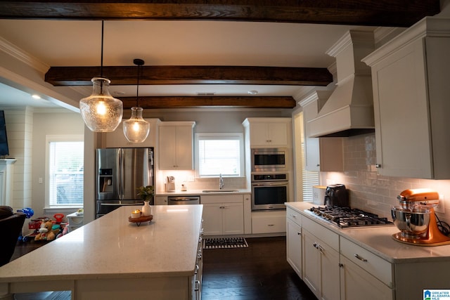 kitchen with sink, hanging light fixtures, appliances with stainless steel finishes, a healthy amount of sunlight, and custom range hood