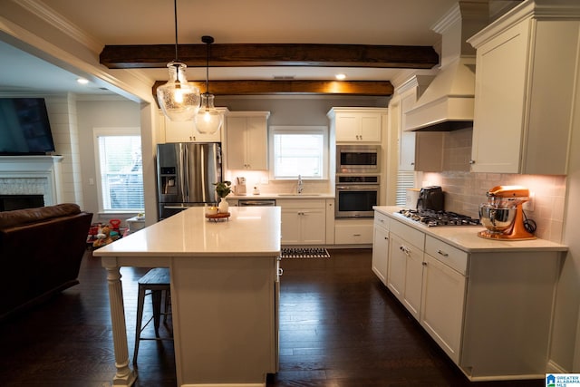 kitchen featuring a kitchen island, a healthy amount of sunlight, custom range hood, and appliances with stainless steel finishes