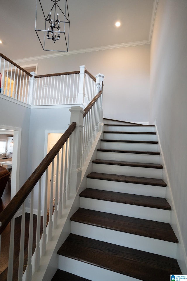 stairway featuring a towering ceiling, an inviting chandelier, and ornamental molding