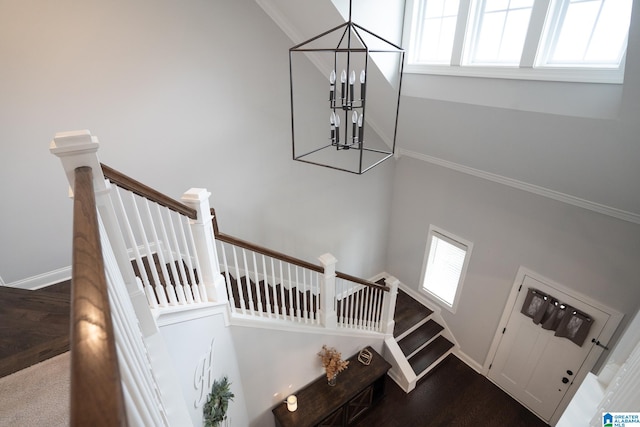 stairway featuring hardwood / wood-style floors, an inviting chandelier, crown molding, and a high ceiling