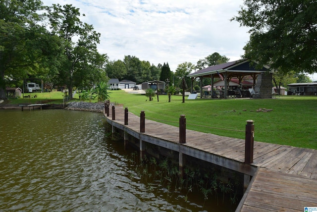 view of dock with a water view, a lawn, and a gazebo