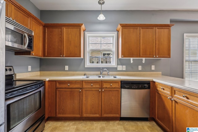 kitchen featuring appliances with stainless steel finishes, a healthy amount of sunlight, sink, and hanging light fixtures