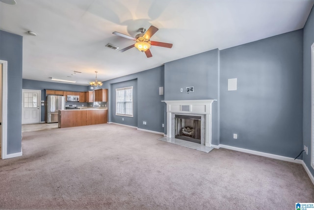 unfurnished living room featuring light colored carpet, ceiling fan with notable chandelier, and a fireplace