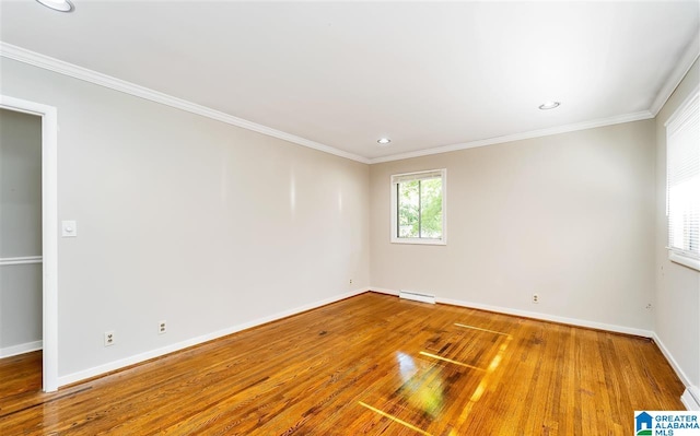 empty room featuring ornamental molding, hardwood / wood-style floors, and a baseboard heating unit