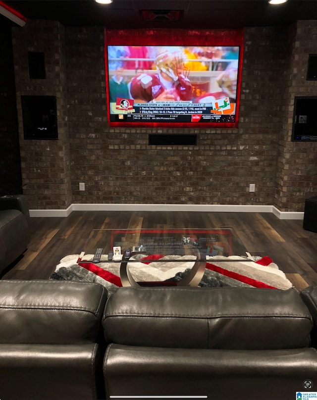 cinema room featuring brick wall and hardwood / wood-style floors