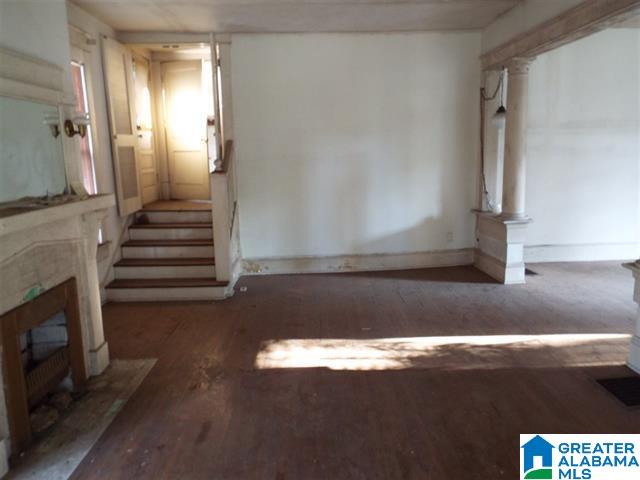 unfurnished living room with dark wood-type flooring and a high end fireplace