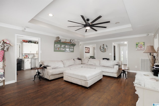 living room with ceiling fan, a raised ceiling, and dark wood-type flooring