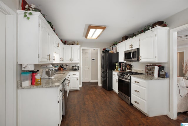 kitchen featuring appliances with stainless steel finishes, white cabinetry, dark hardwood / wood-style flooring, and sink