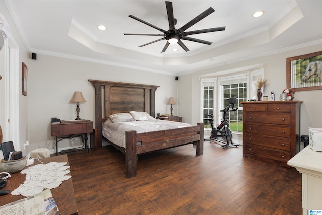 bedroom featuring ceiling fan, a tray ceiling, dark wood-type flooring, and ornamental molding