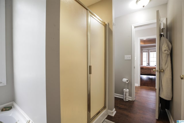 bathroom with wood-type flooring and shower with separate bathtub