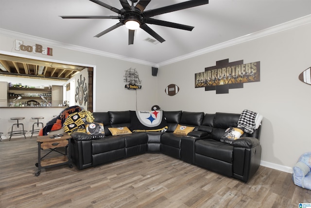 living room featuring ceiling fan, hardwood / wood-style flooring, bar area, and crown molding