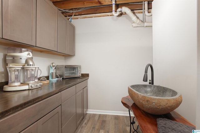 kitchen with gray cabinetry, wood-type flooring, and sink