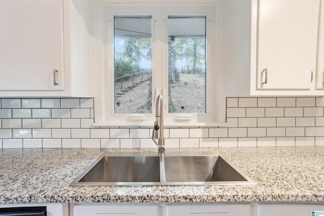 kitchen with light stone counters, sink, decorative backsplash, and white cabinets