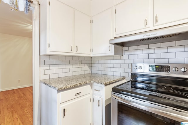 kitchen with stainless steel electric range oven, light hardwood / wood-style flooring, light stone countertops, and white cabinets