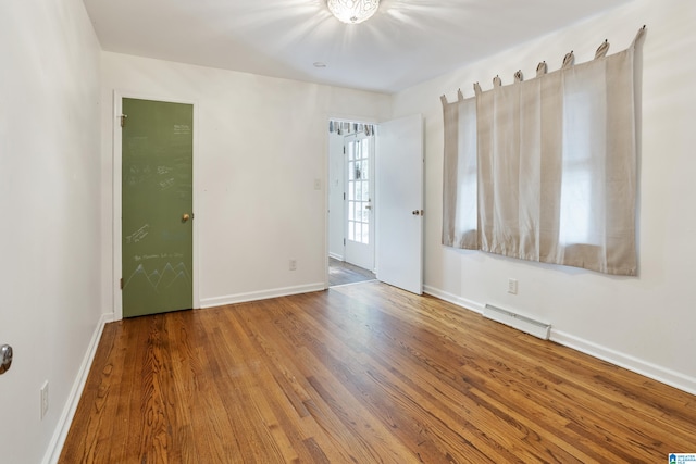 unfurnished room featuring hardwood / wood-style floors and a baseboard radiator