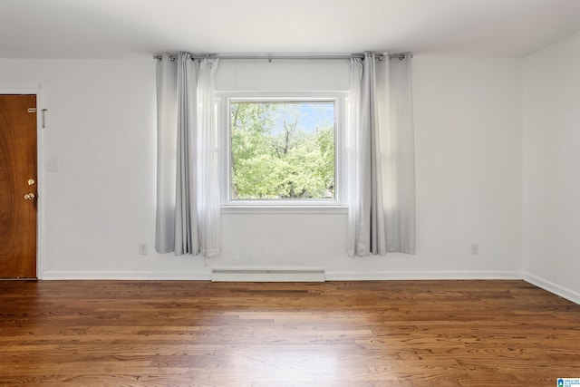 unfurnished room with hardwood / wood-style floors and baseboard heating