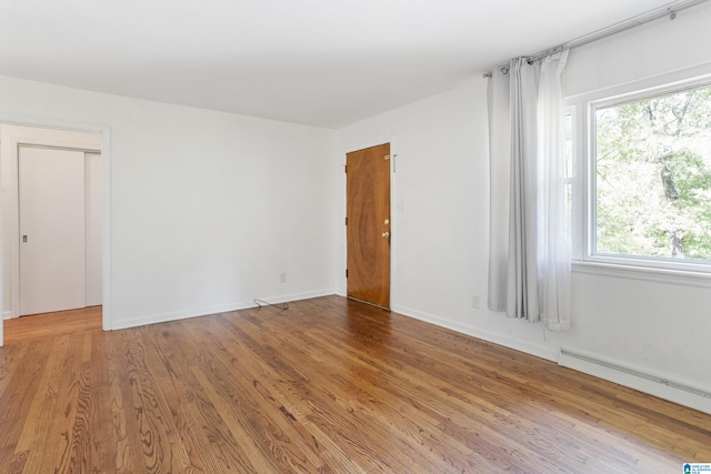 empty room with baseboard heating and hardwood / wood-style floors