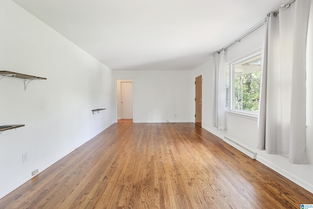 unfurnished room with baseboard heating and wood-type flooring