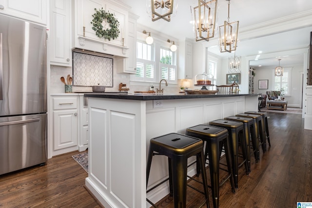 kitchen featuring a center island, white cabinetry, a healthy amount of sunlight, and stainless steel refrigerator